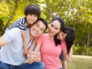 asian_family_with_two_children_taking_a_family_photo_outdoors_in_a_city_park