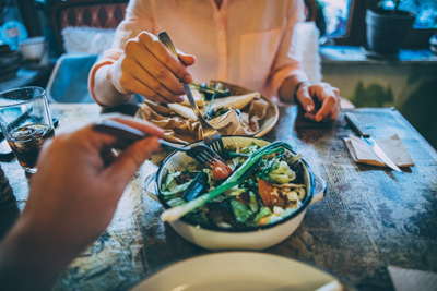 Woman taking some of her boyfriend's salad on lunch at a restaurant.