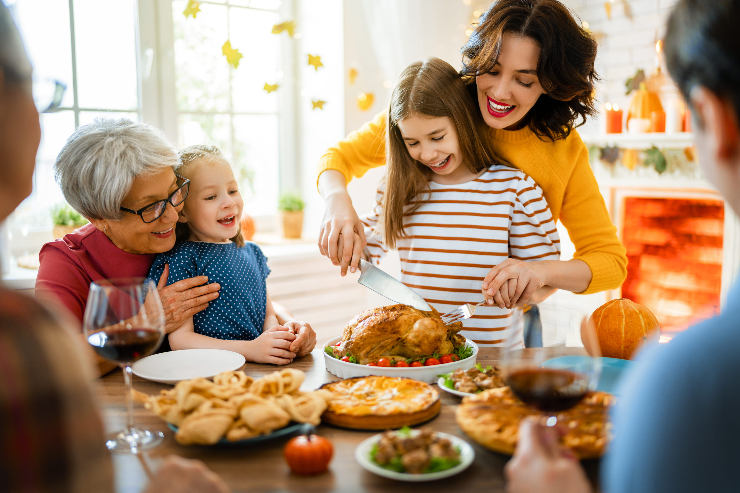 Happy Thanksgiving Day! Autumn feast. Family sitting at the table and celebrating holiday. Grandparents, mother, father and children. Traditional dinner.
