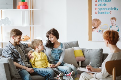 Caring parents and misbehaving boy during therapy session with counselor